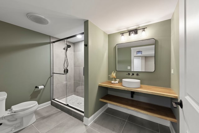 bathroom with a shower with door, vanity, tile patterned flooring, and toilet