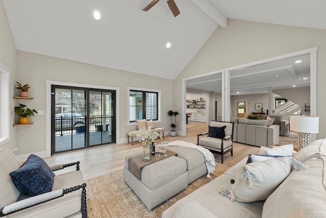 living room with ceiling fan, high vaulted ceiling, beamed ceiling, and light wood-type flooring