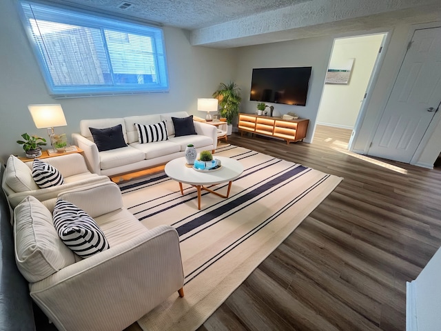 living room with a textured ceiling and dark wood-type flooring