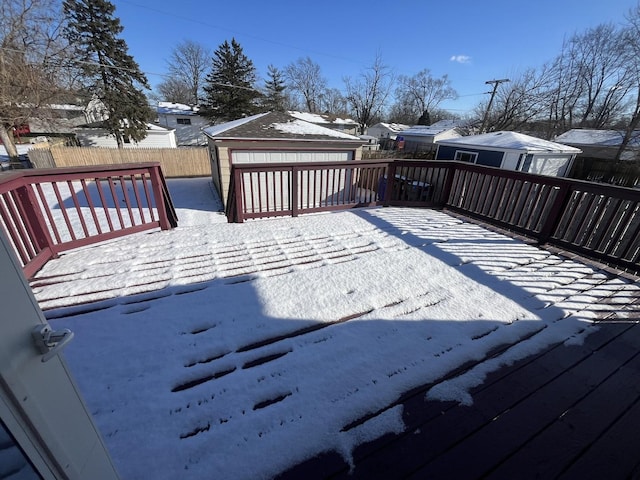 snow covered deck with a garage and an outdoor structure