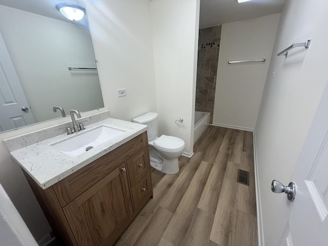 full bathroom with hardwood / wood-style flooring, vanity, toilet, and tiled shower / bath