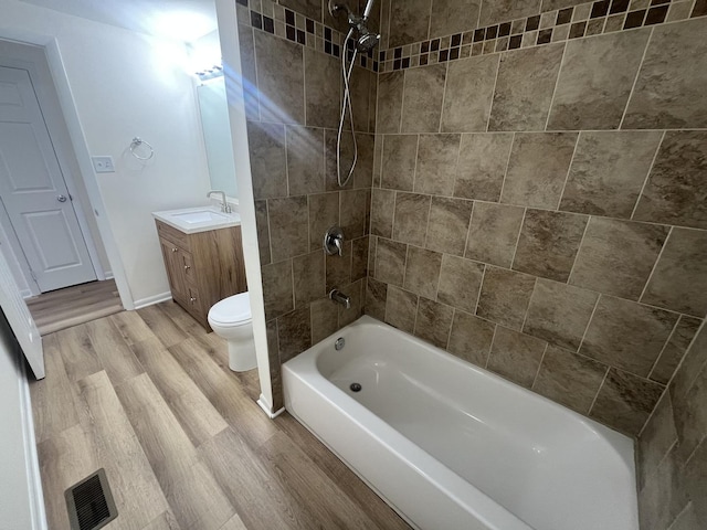 full bathroom featuring vanity, toilet, wood-type flooring, and tiled shower / bath