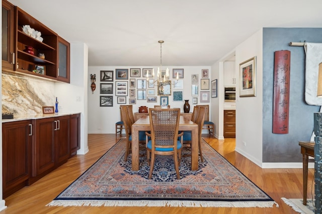 dining area with light hardwood / wood-style flooring and a chandelier