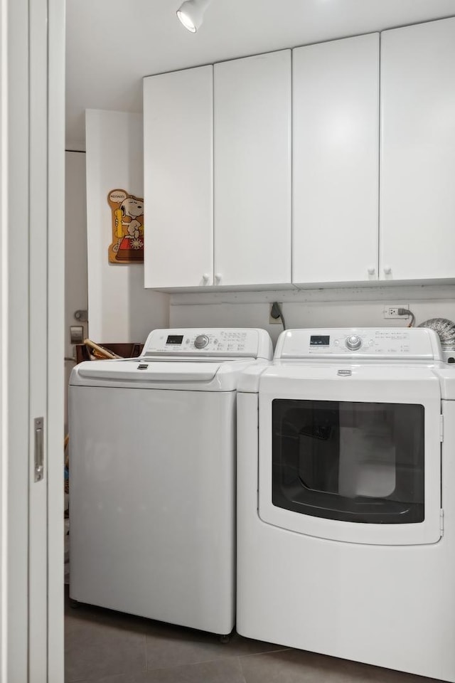 clothes washing area featuring cabinets, dark tile patterned flooring, and independent washer and dryer