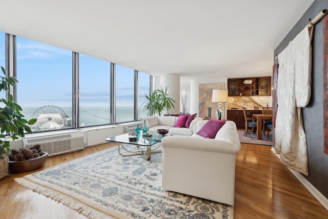 living room with hardwood / wood-style floors, a water view, and a wall mounted AC