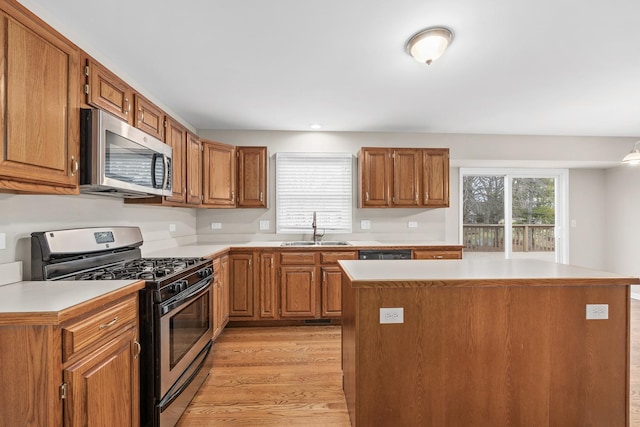 kitchen with sink, a kitchen island, stainless steel appliances, and light wood-type flooring