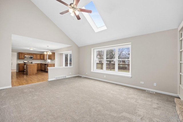 unfurnished living room featuring ceiling fan with notable chandelier, light colored carpet, sink, and high vaulted ceiling