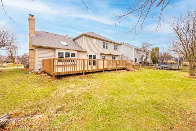 rear view of property featuring a trampoline, a yard, and a wooden deck