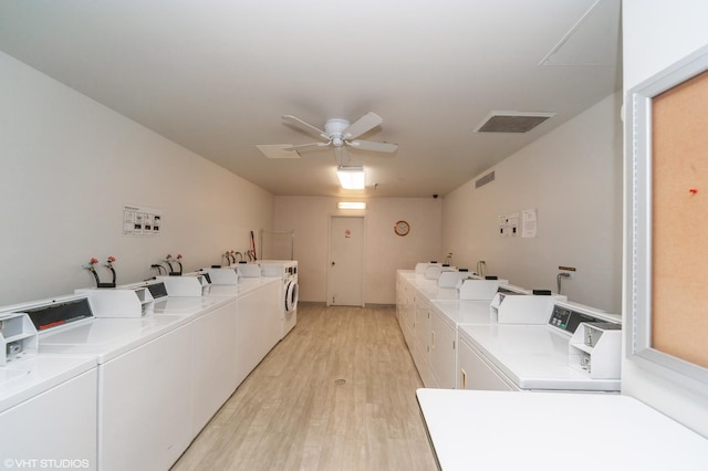 clothes washing area with washing machine and clothes dryer, ceiling fan, and light hardwood / wood-style flooring