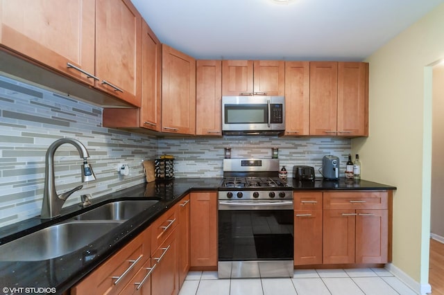 kitchen with appliances with stainless steel finishes, light tile patterned flooring, backsplash, and sink