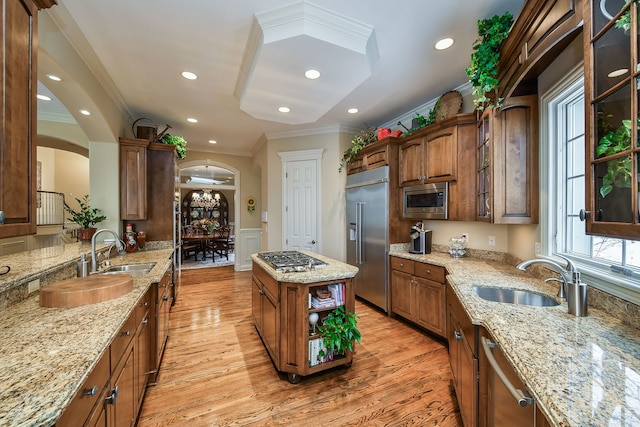 kitchen featuring ornamental molding, sink, built in appliances, and light stone counters