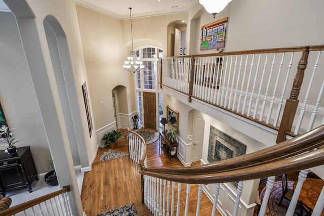 interior space with hardwood / wood-style flooring, ornamental molding, a high ceiling, and a notable chandelier