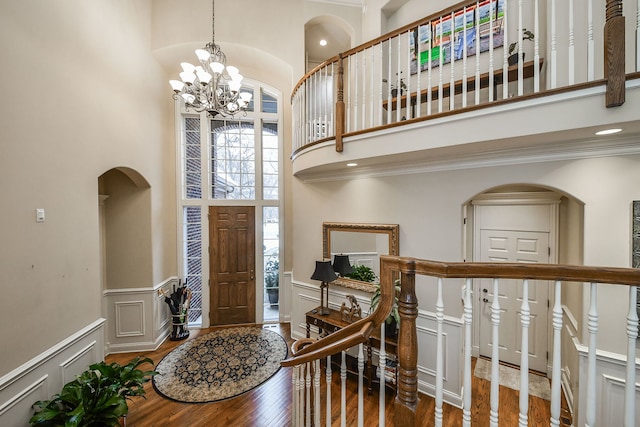 foyer entrance featuring hardwood / wood-style floors, a towering ceiling, a wealth of natural light, and a chandelier