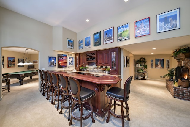 bar with light carpet, pendant lighting, a fireplace, and pool table