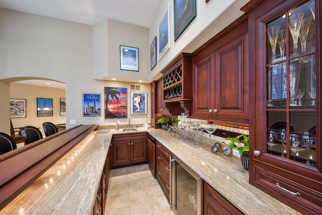 bar with light stone countertops, sink, light tile patterned floors, and wine cooler