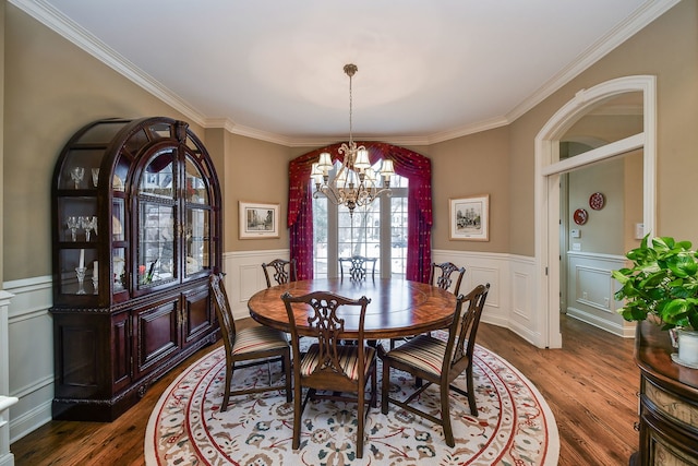 dining space featuring wood-type flooring, crown molding, and a chandelier