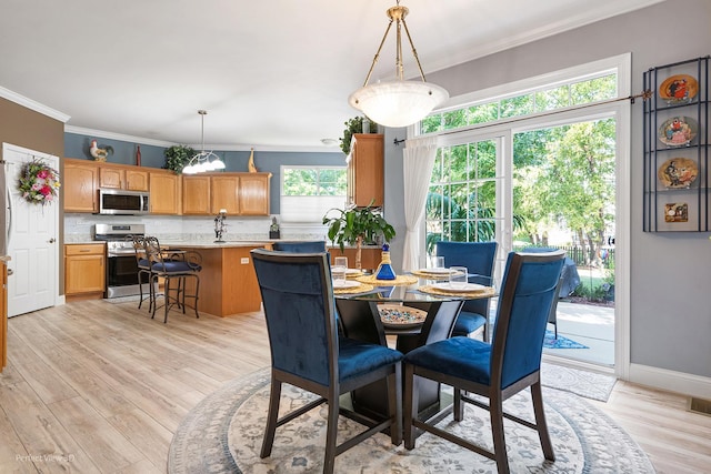 dining room featuring light wood-type flooring and crown molding