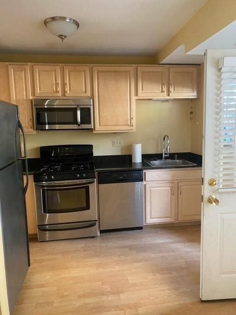 kitchen featuring light brown cabinetry, sink, light wood-type flooring, and appliances with stainless steel finishes