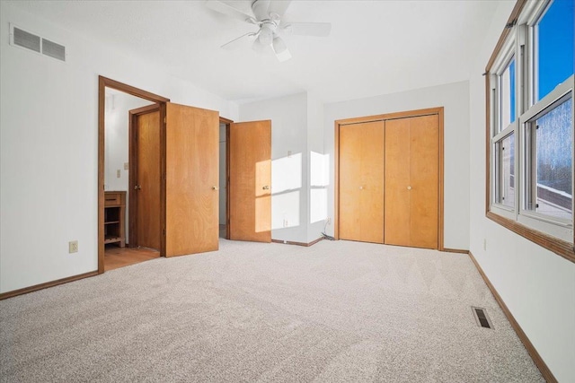 unfurnished bedroom featuring ceiling fan, light colored carpet, and a closet