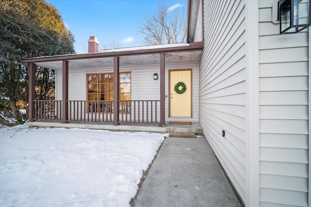 snow covered property entrance with covered porch