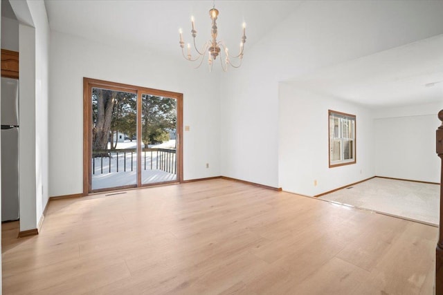 empty room with a chandelier and light wood-type flooring