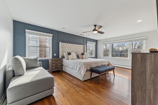 bedroom with ceiling fan, a baseboard radiator, and wood-type flooring