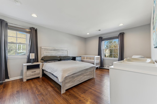 bedroom featuring dark hardwood / wood-style flooring, multiple windows, and baseboard heating