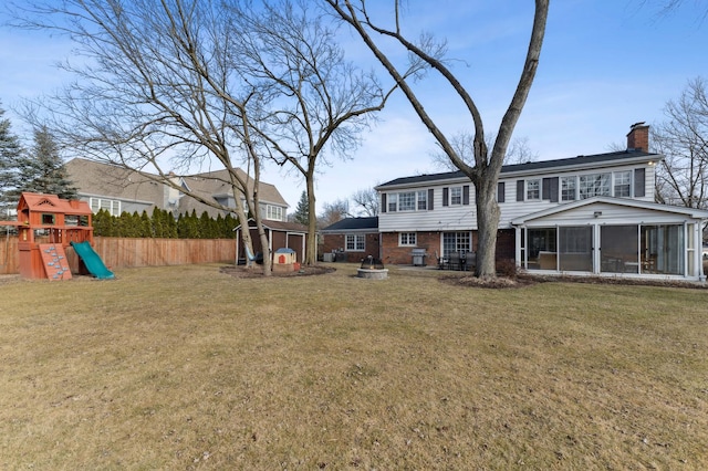 back of house with a playground, a sunroom, a yard, and a storage shed