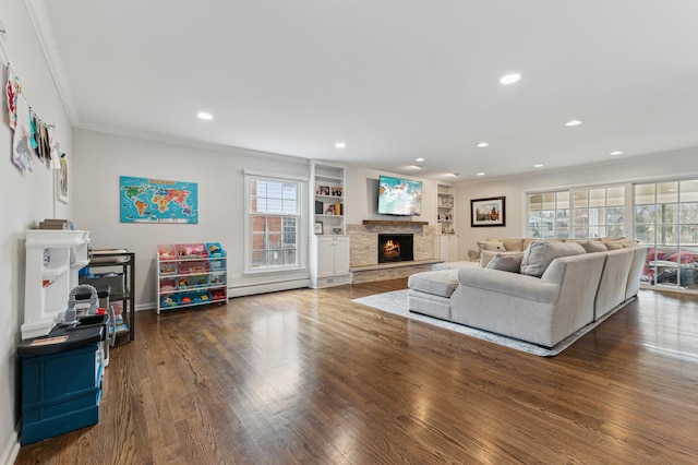 living room with crown molding, baseboard heating, dark hardwood / wood-style floors, a fireplace, and built in shelves