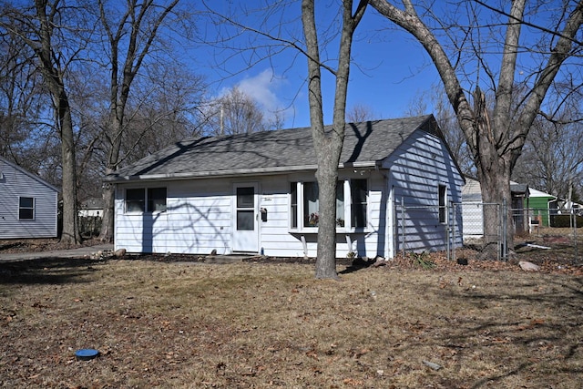 ranch-style house featuring roof with shingles and fence