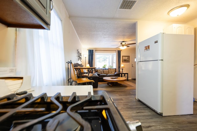 kitchen with a textured ceiling, visible vents, a ceiling fan, freestanding refrigerator, and dark wood finished floors