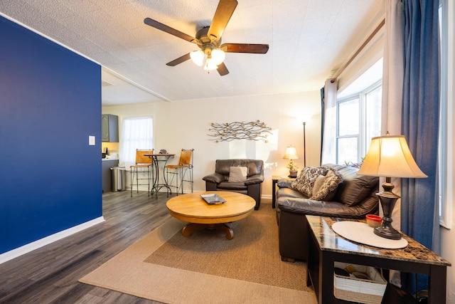 living room with a ceiling fan, baseboards, and wood finished floors