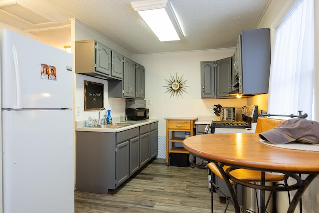 kitchen featuring black microwave, a sink, freestanding refrigerator, and gray cabinetry