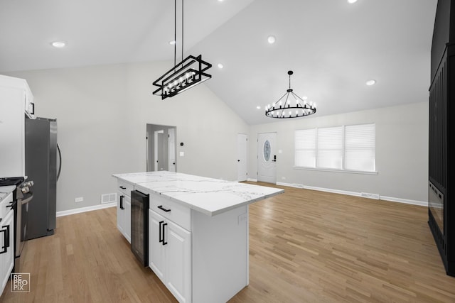 kitchen with pendant lighting, a center island, light wood-type flooring, white cabinetry, and beverage cooler