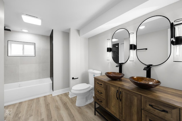 full bathroom with hardwood / wood-style floors, vanity, toilet, and tiled shower / bath