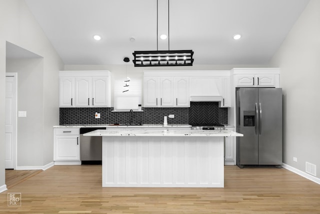 kitchen featuring pendant lighting, a kitchen island, white cabinets, and stainless steel appliances