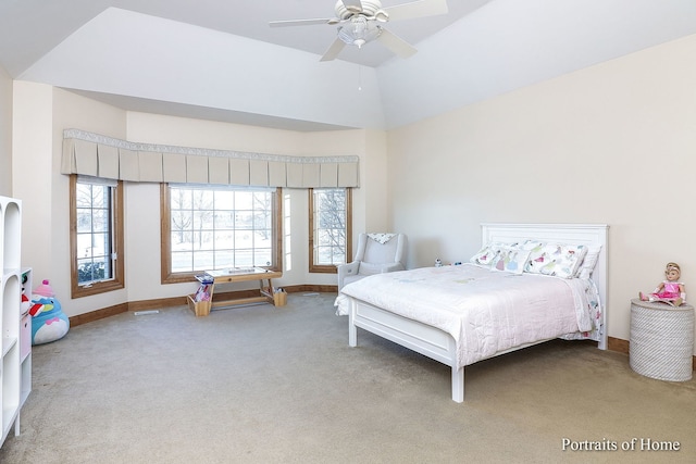 carpeted bedroom with ceiling fan, multiple windows, and a raised ceiling