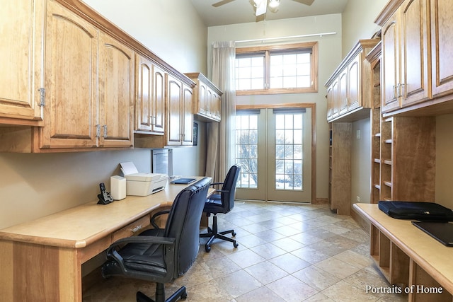 office with built in desk, french doors, a towering ceiling, and ceiling fan