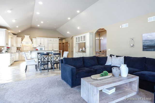 living room featuring light tile patterned flooring, a chandelier, and lofted ceiling