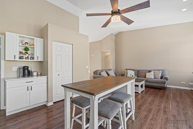 dining area with ceiling fan, dark hardwood / wood-style floors, and vaulted ceiling