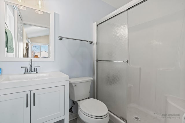 bathroom featuring toilet, a shower with shower door, and vanity