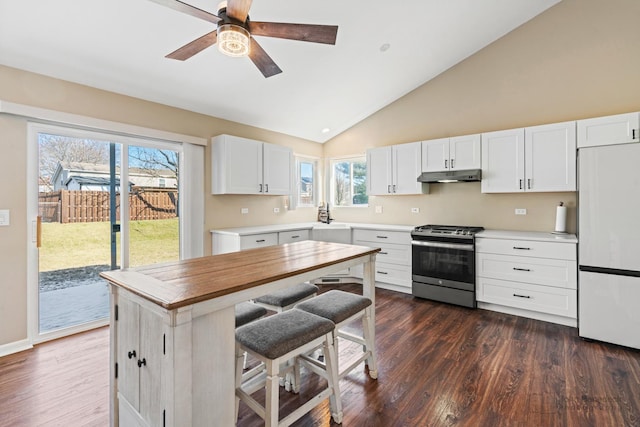 kitchen with white fridge, dark hardwood / wood-style flooring, white cabinets, and stainless steel gas range oven