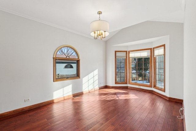 empty room featuring hardwood / wood-style flooring, lofted ceiling, and an inviting chandelier