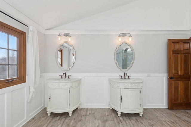 bathroom featuring hardwood / wood-style flooring, vanity, ornamental molding, and vaulted ceiling