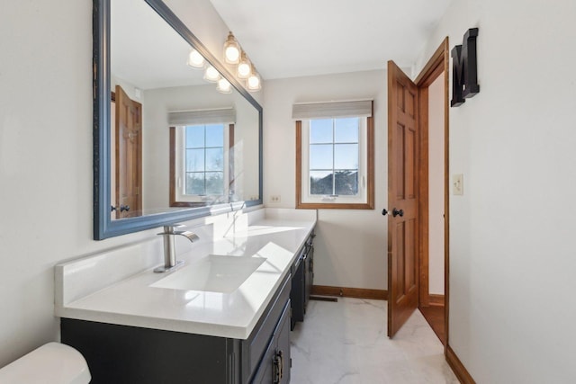 bathroom featuring toilet, vanity, and a healthy amount of sunlight