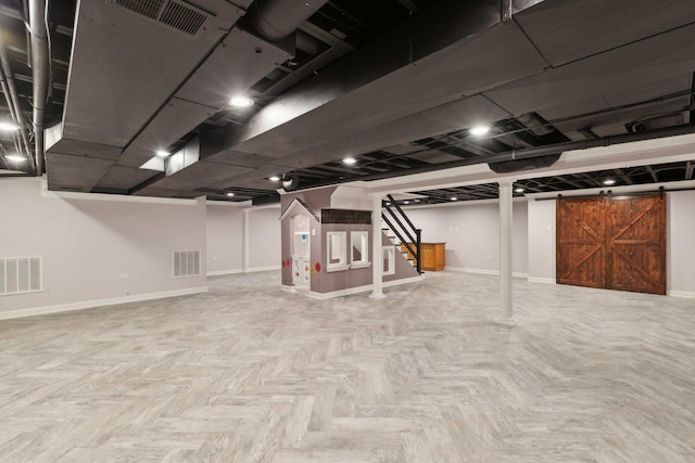 basement featuring light parquet flooring and a barn door