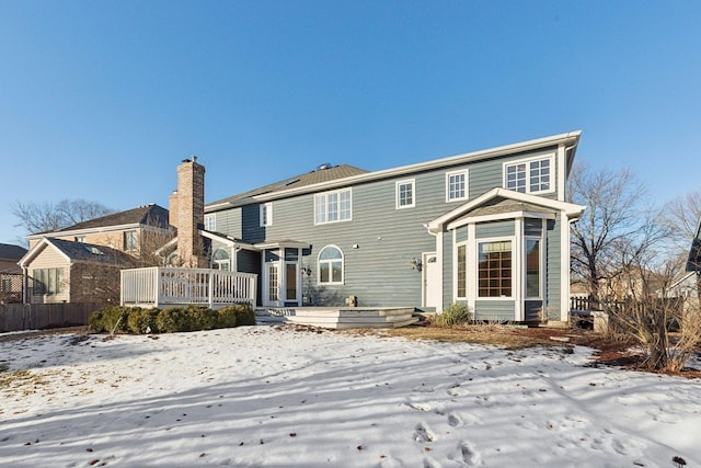 snow covered rear of property with a deck