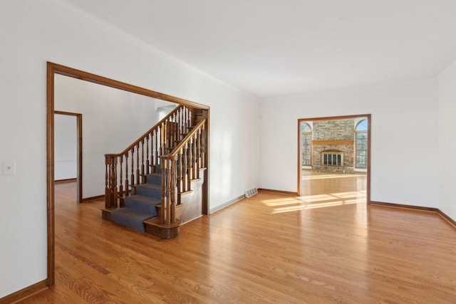 unfurnished living room with a fireplace, light hardwood / wood-style flooring, and crown molding