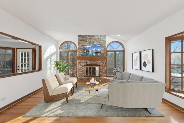 living room with a fireplace, light hardwood / wood-style flooring, and vaulted ceiling