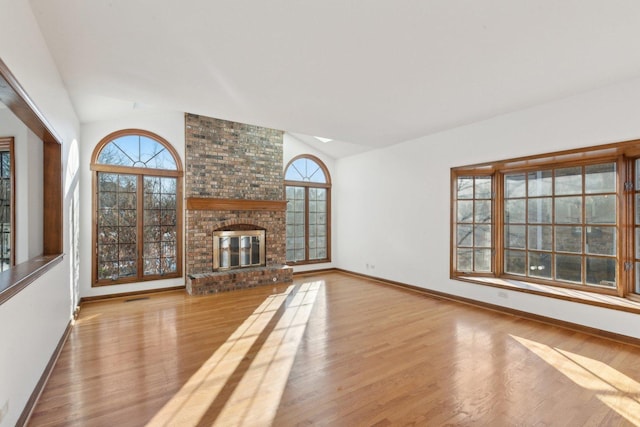 unfurnished living room featuring light hardwood / wood-style floors, lofted ceiling, and a fireplace